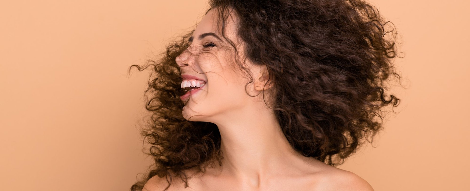 Modelo branca sorrindo com cabelo cacheado