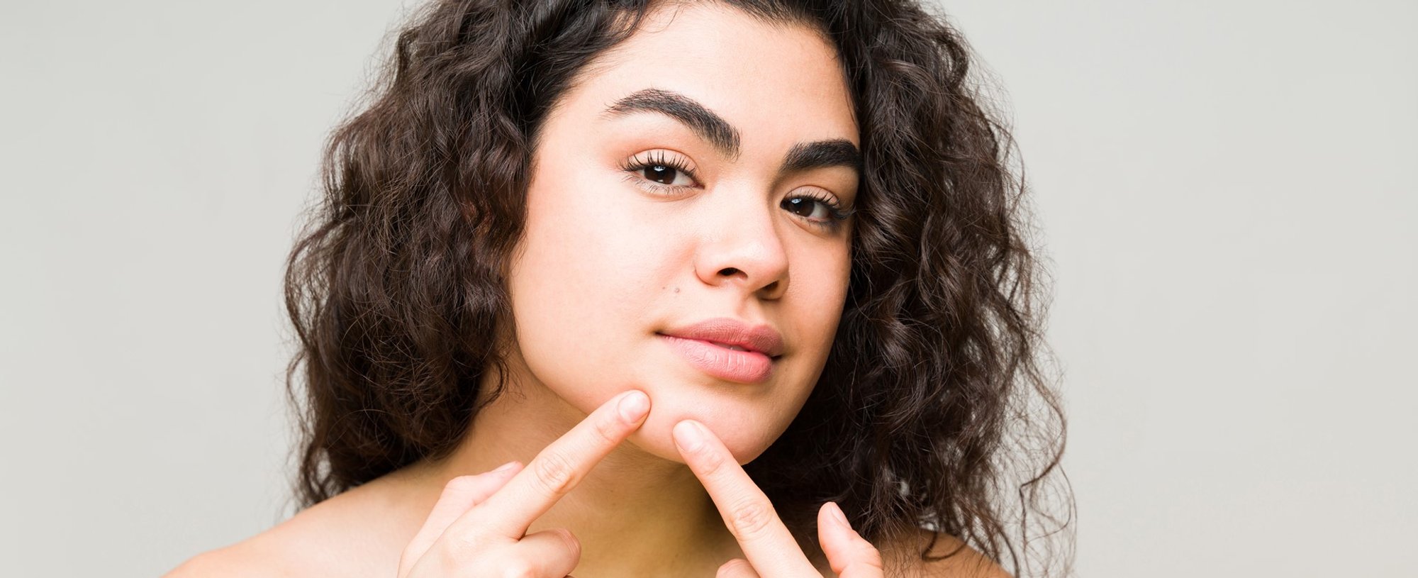 Modelo branca apertando acne do seu rosto