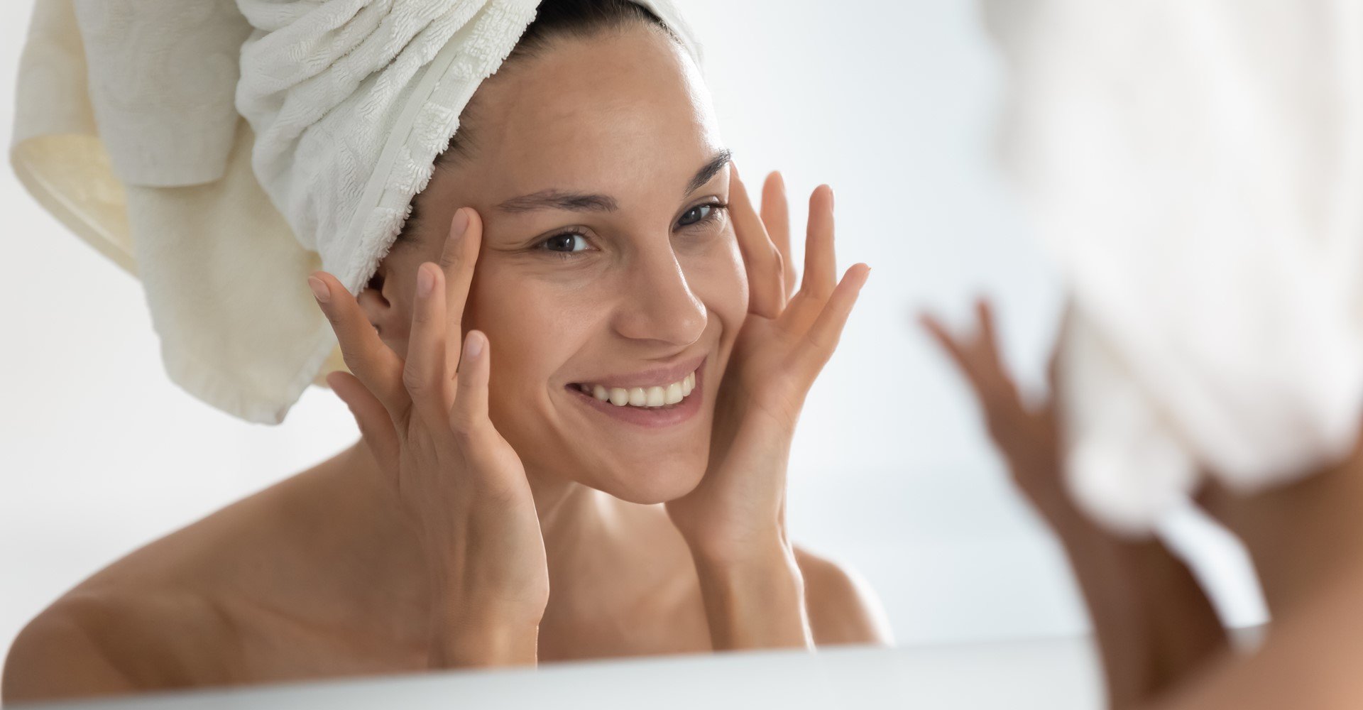 Modelo branca sorrindo com as mãos no rosto