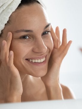Modelo branca sorrindo com as mãos no rosto