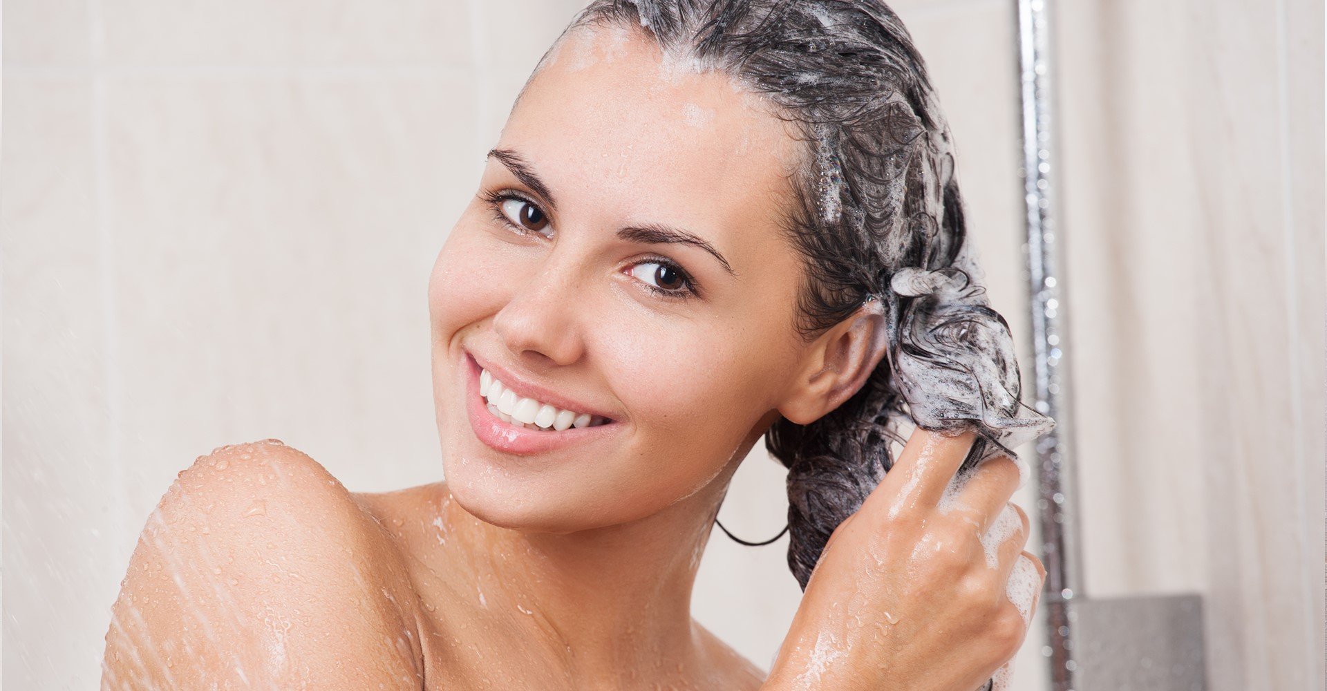 Modelo branca sorrindo lavando seus cabelos