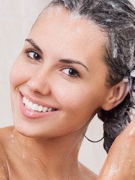 Modelo branca sorrindo lavando seus cabelos