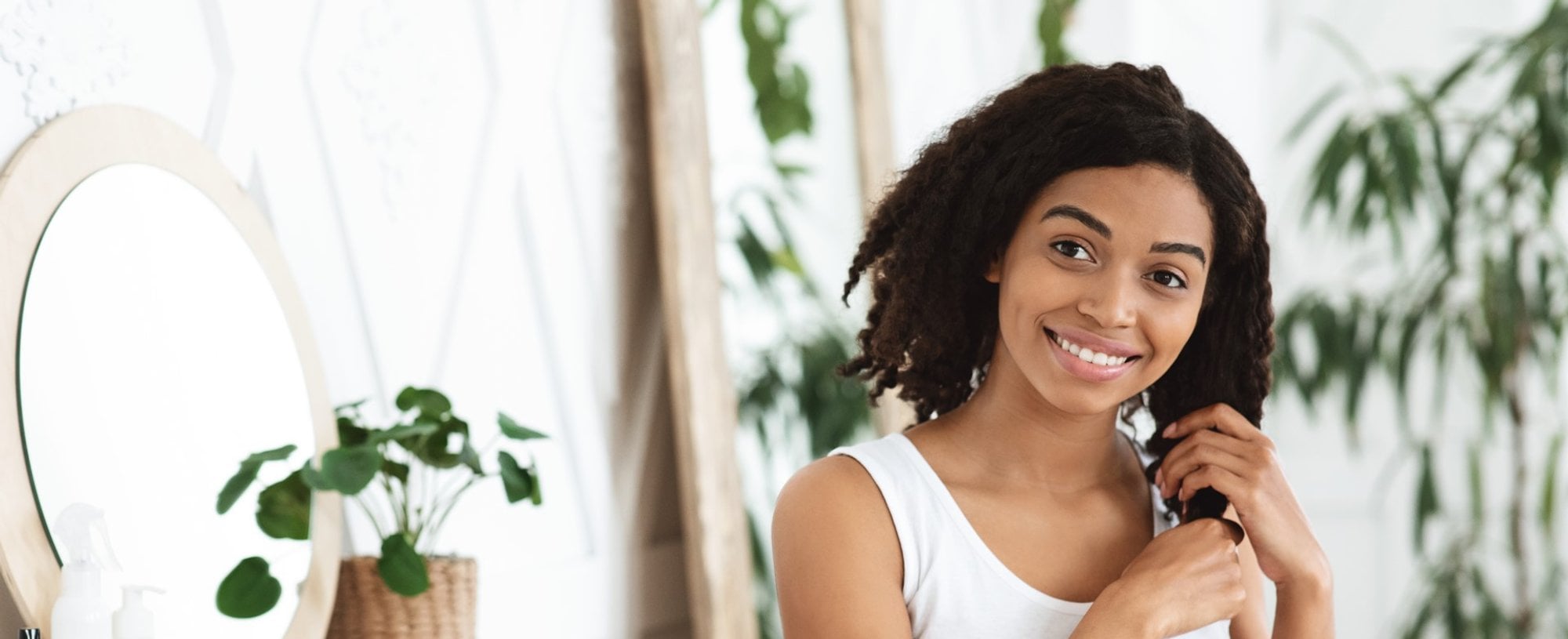 Modelo negra sorrindo com as mãos no cabelo