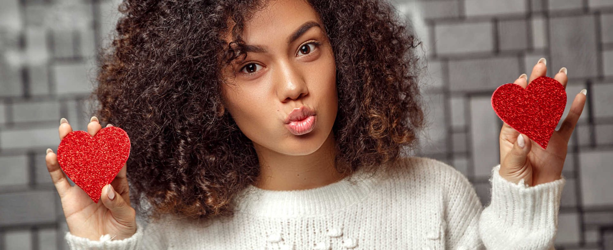 Modelo negra com dois corações vermelhos na mão