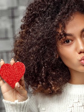 Modelo negra com dois corações vermelhos na mão