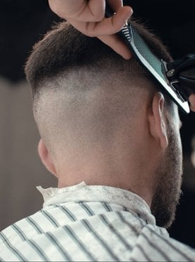Profissional fazendo corte em cabelo de modelo branco