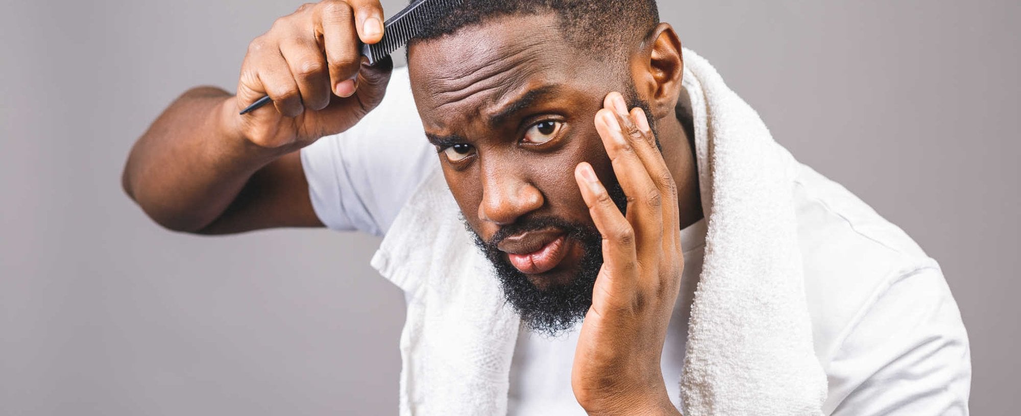 Modelo negro passando pente em seu cabelo com corte baixo
