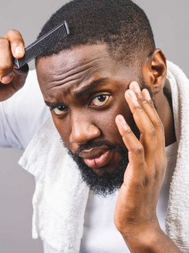 Modelo negro passando pente em seu cabelo com corte baixo