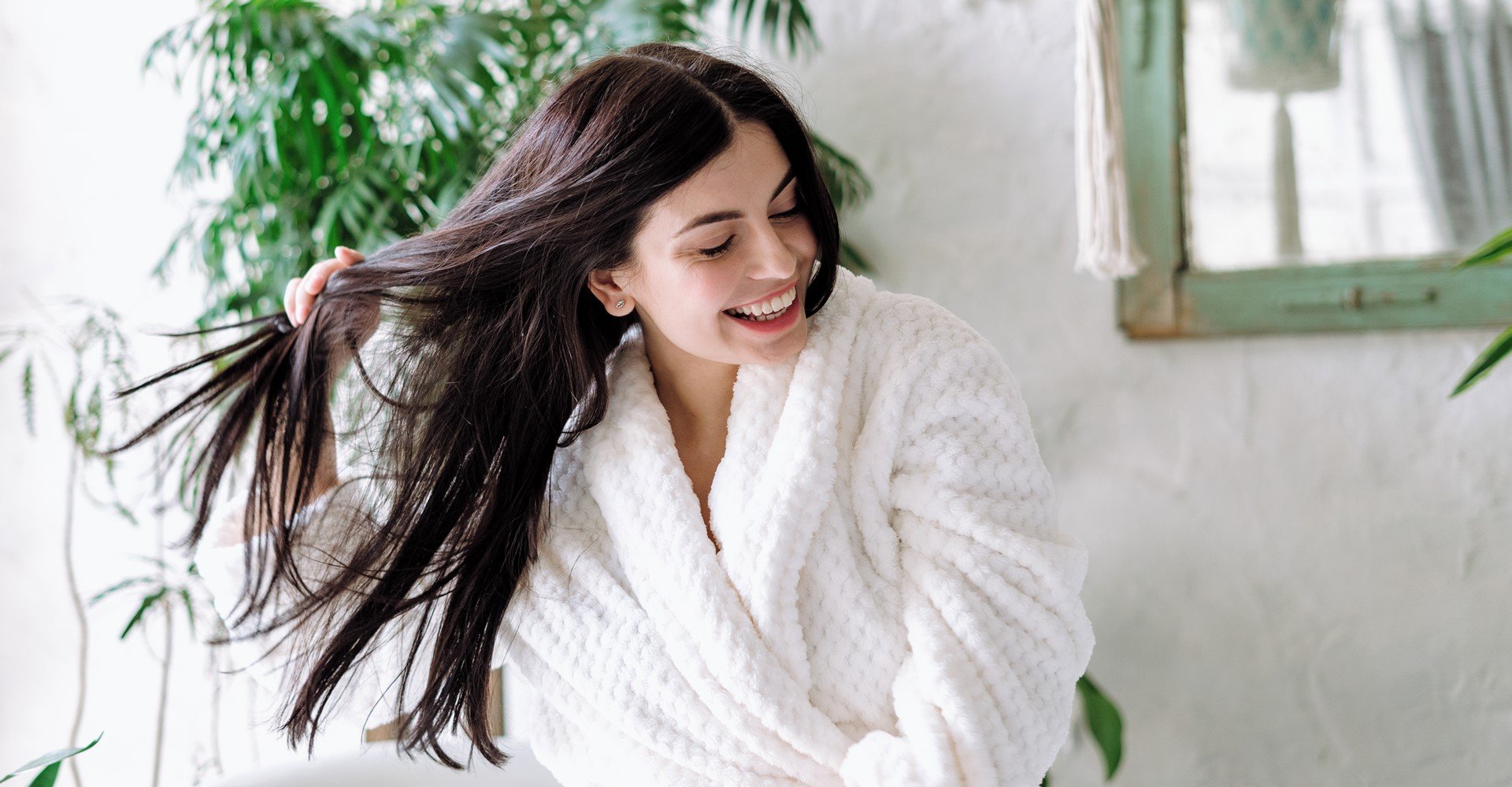 Modelo branca sorrindo com a mão em seus cabelos lisos