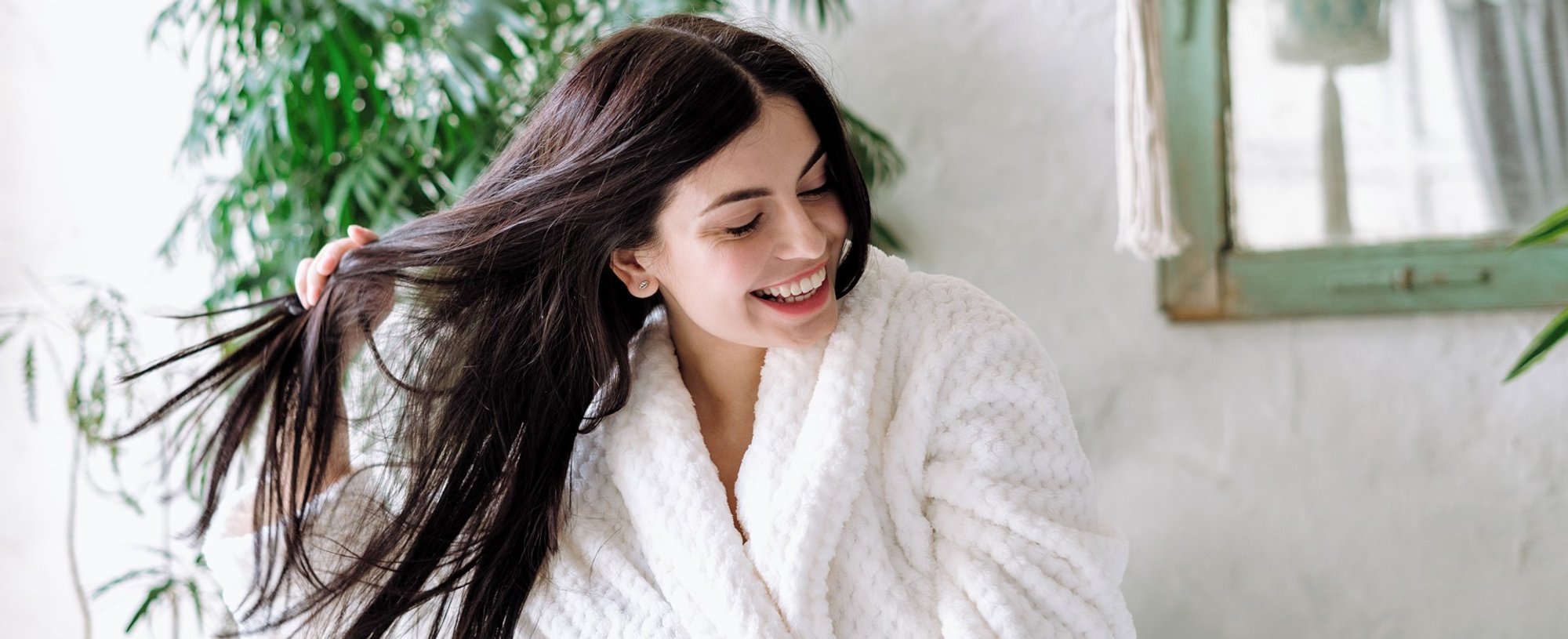 Modelo branca sorrindo com a mão em seus cabelos lisos
