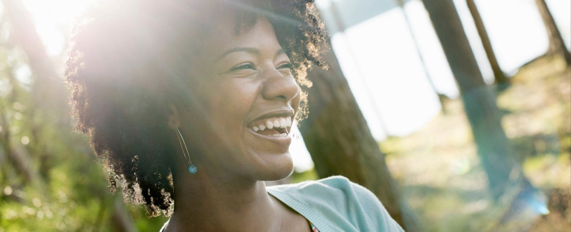 Modelo negra sorrindo com cabelo curto e crespo