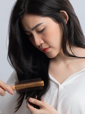 Modelo branca passando escova no cabelo