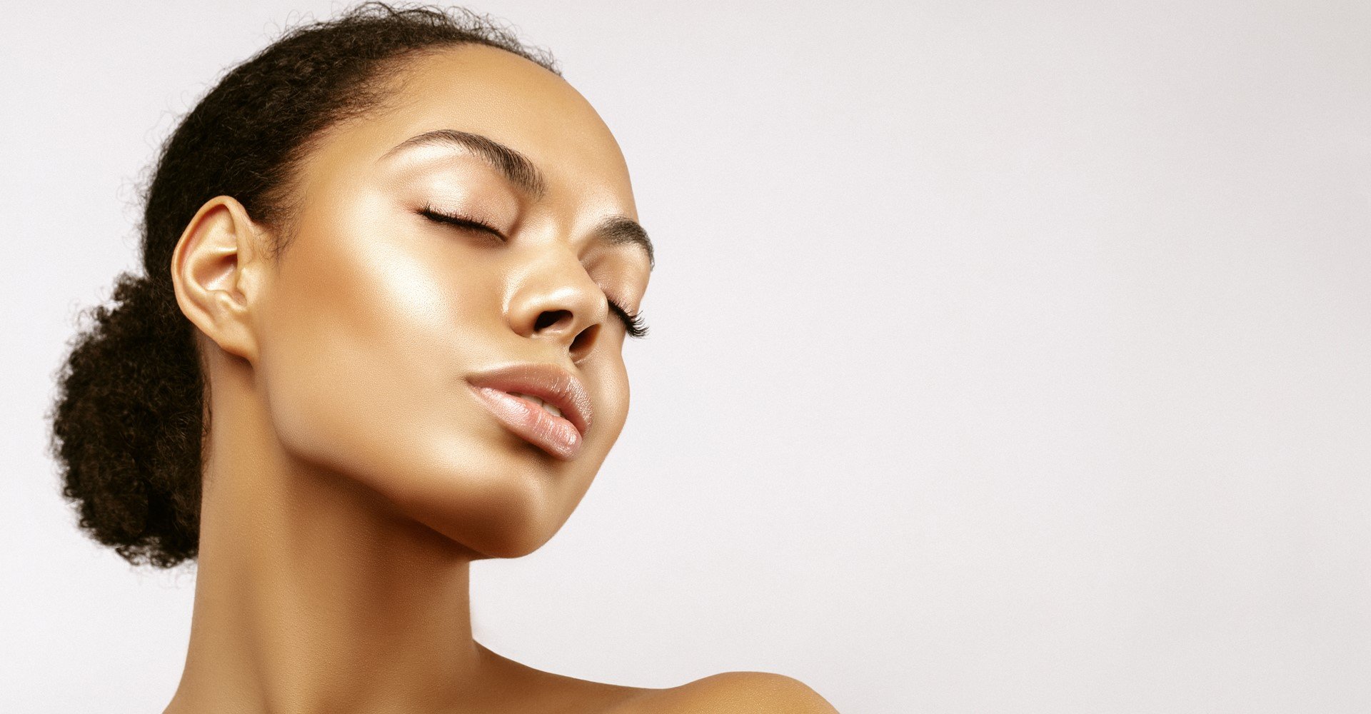 Modelo negra com cabelo cacheado amarrado de coque