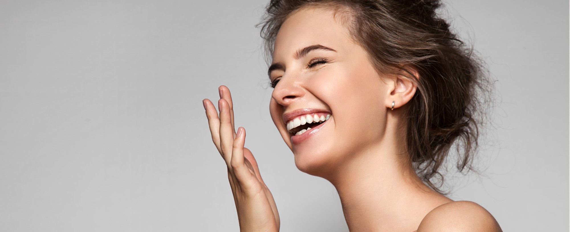 Modelo branca sorrindo com cabelo liso amarrado de coque