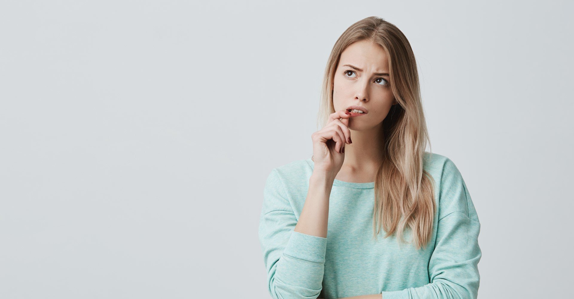 Modelo branca com cabelo loiro e liso, com expressão de dúvida