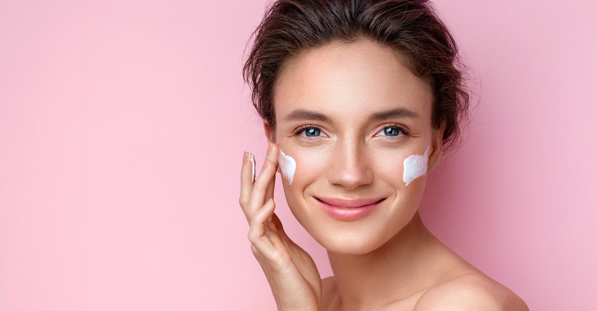 Modelo branca sorrindo com creme no rosto