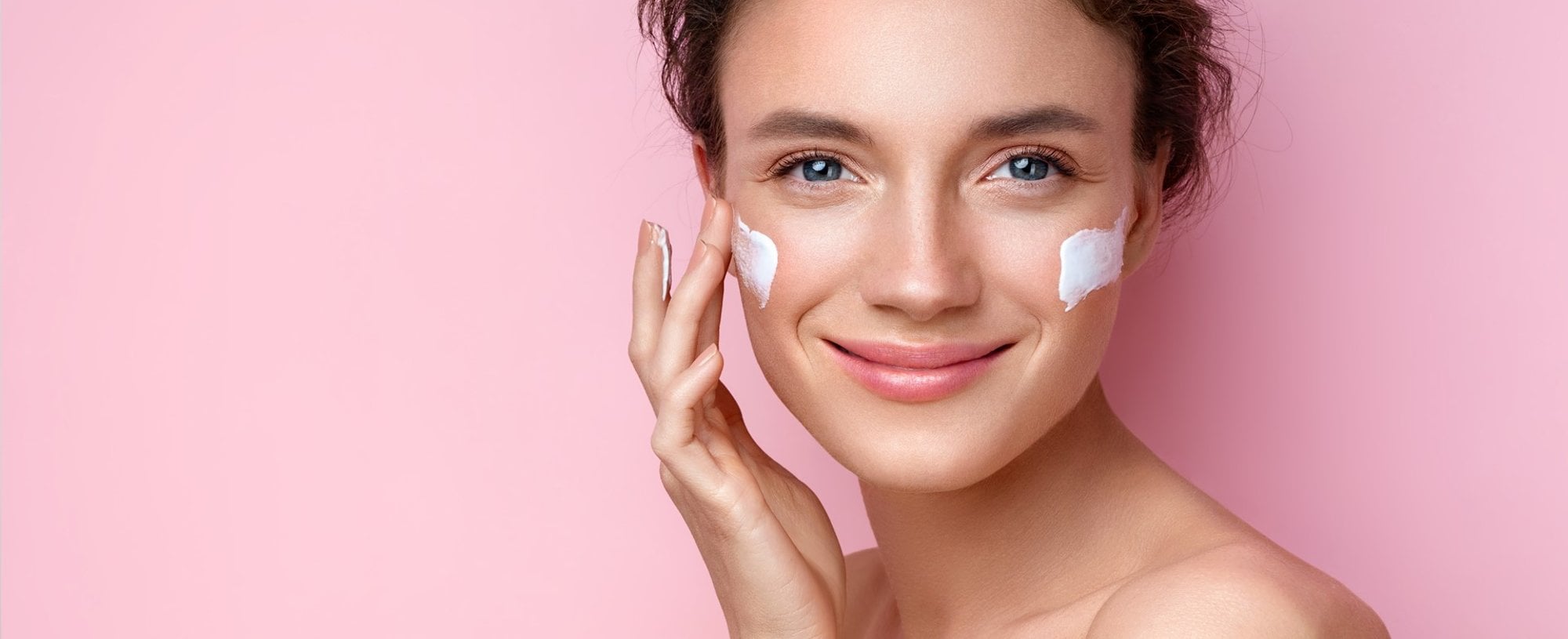 Modelo branca sorrindo com creme no rosto