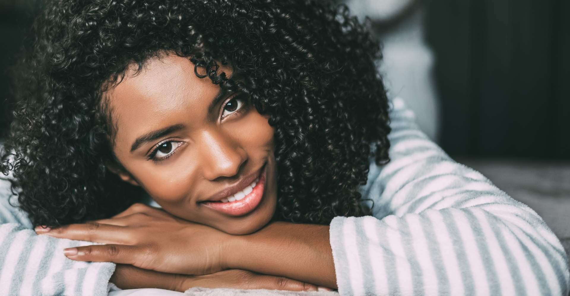 Modelo negra sorrindo com cabelo cacheado