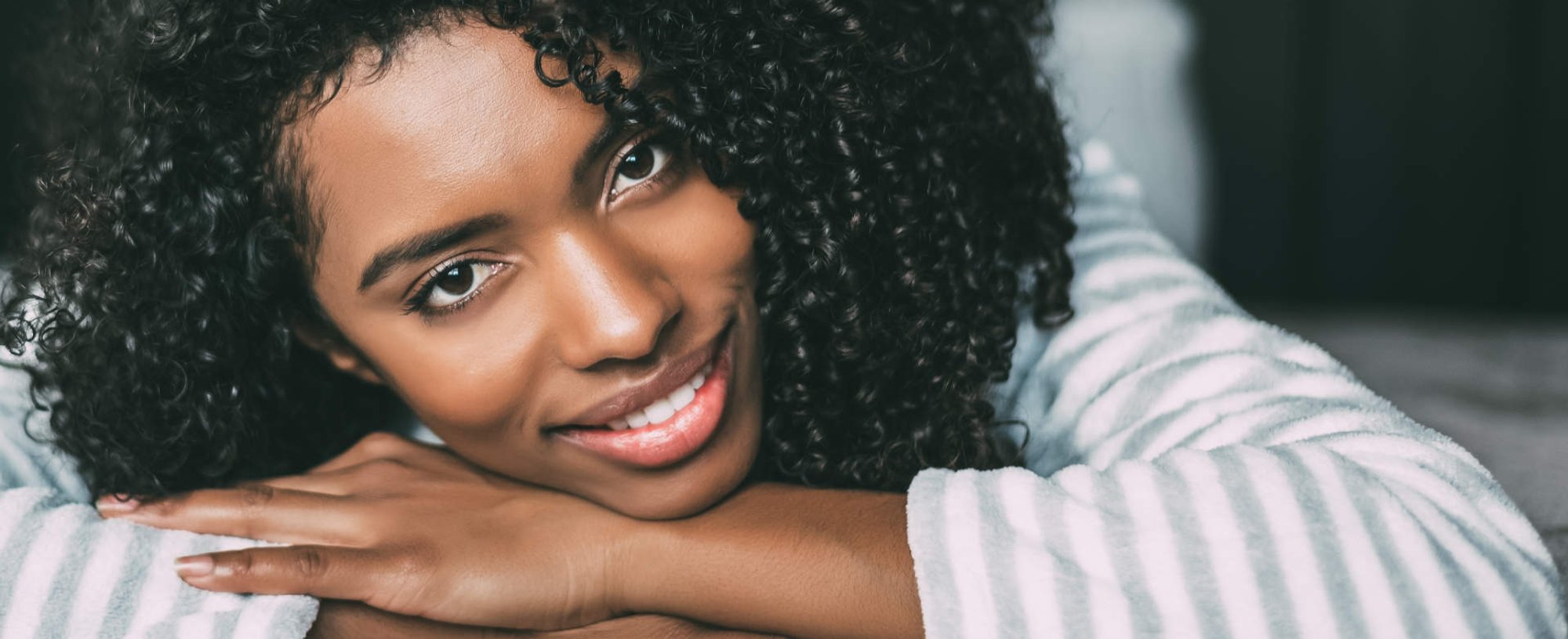 Modelo negra sorrindo com cabelo cacheado