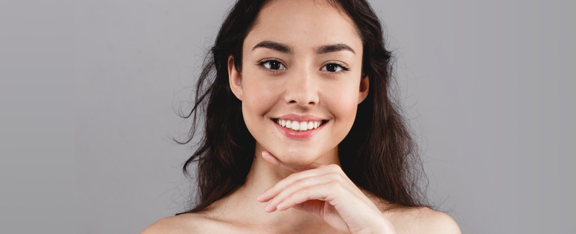 Modelo branca sorrindo com a mão no queixo