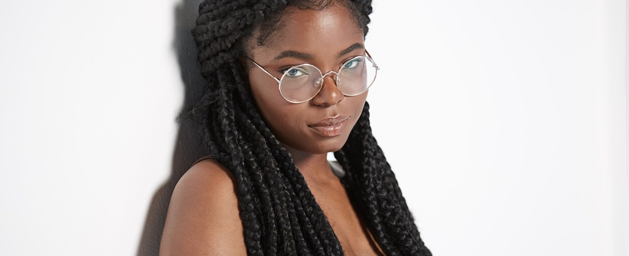 Modelo negra com tranças no cabelo e óculos de grau posando para a foto