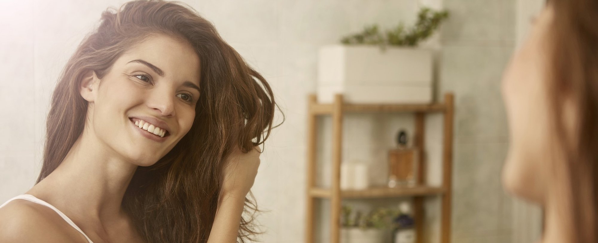 Modelo branca sorrindo se olhando no espelho