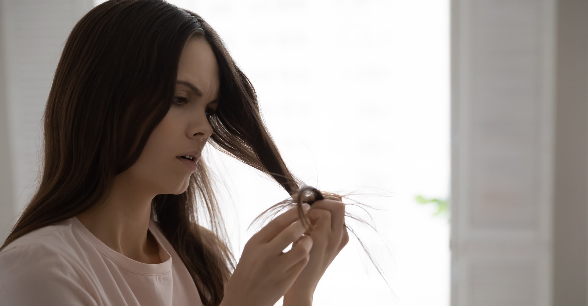 Modelo branca analisando as pontas do seu cabelo