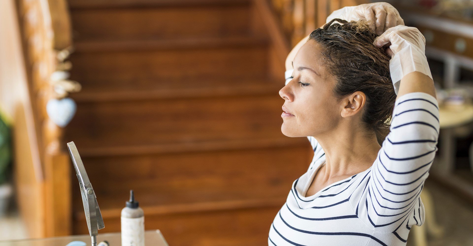 Modelo branca se olhando no espelho pintando seus cabelos