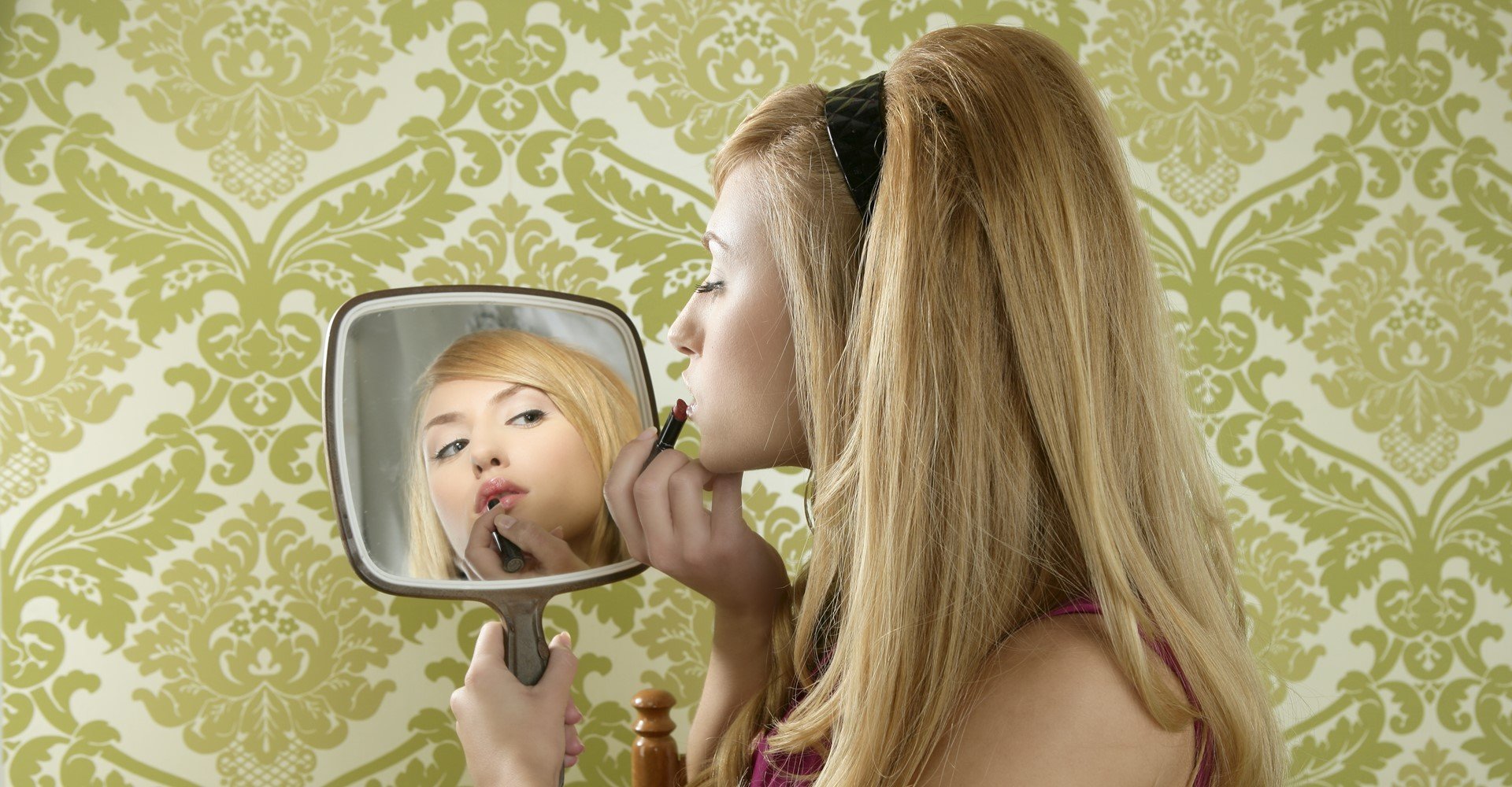 Modelo loira se olhando no espelho com tiara preta na cabeça