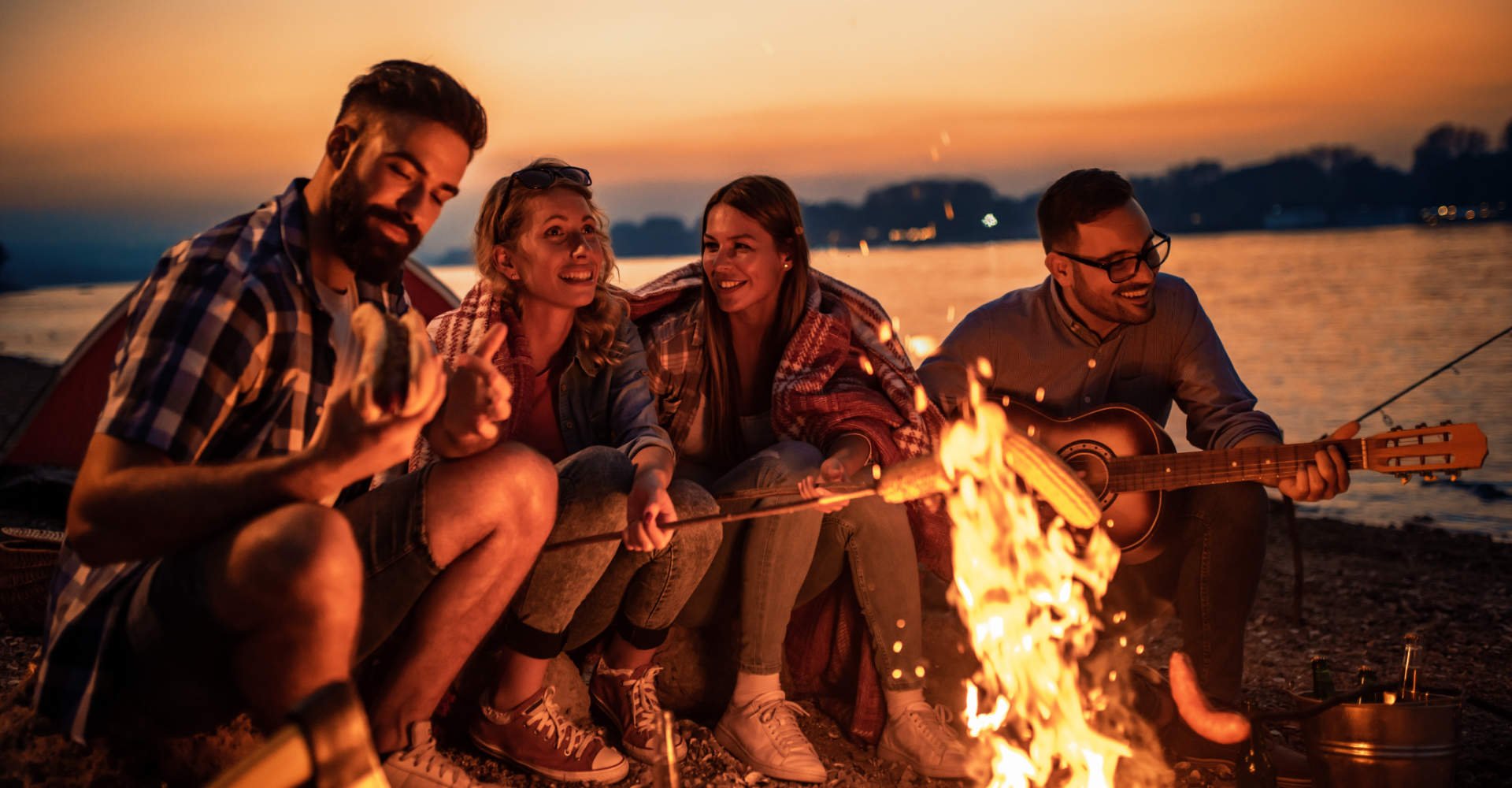 Grupos de amigos na praia conversando ao redor de uma fogueira