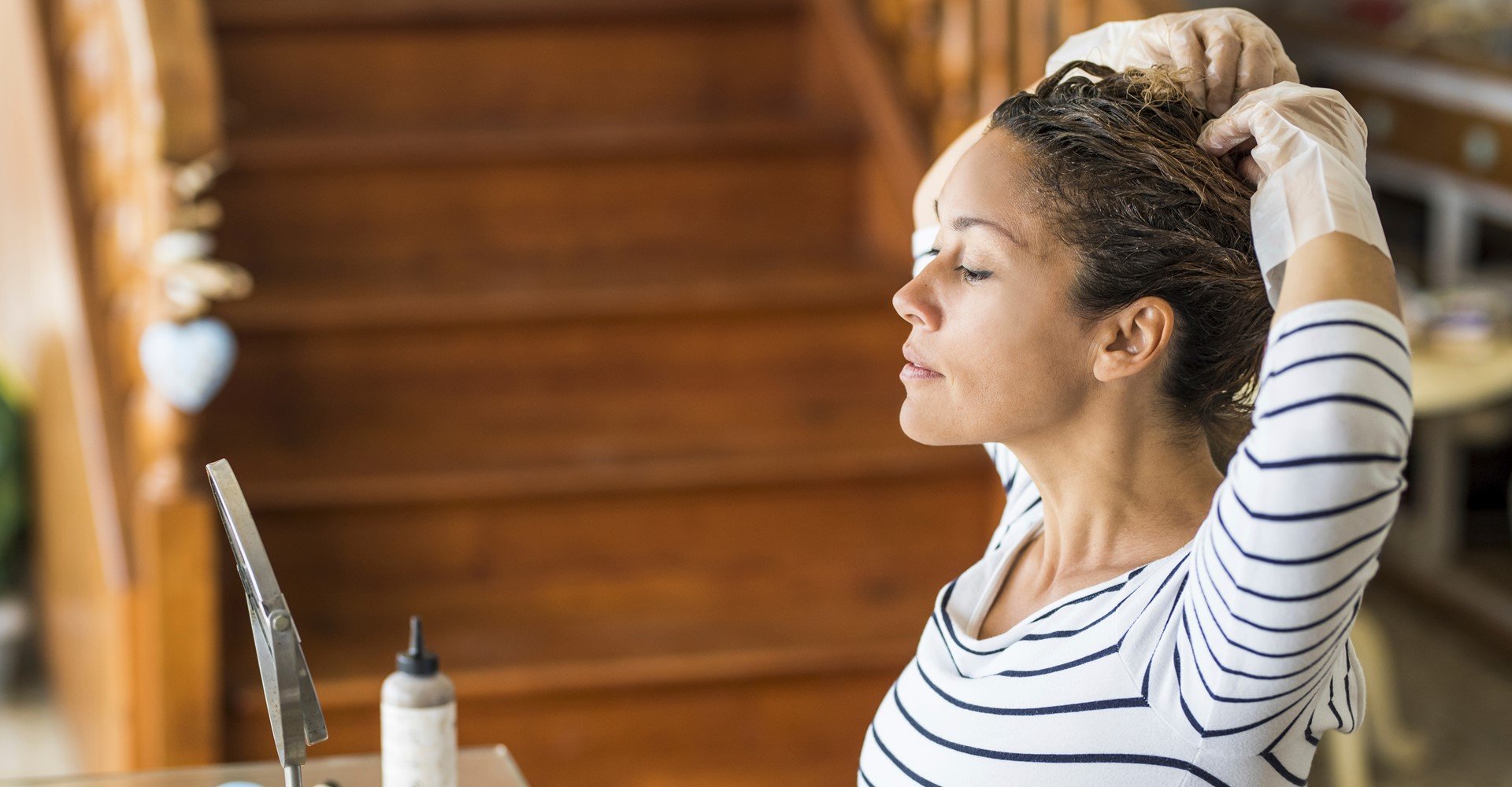 Modelo branca se olhando no espelho e pintando seus cabelos