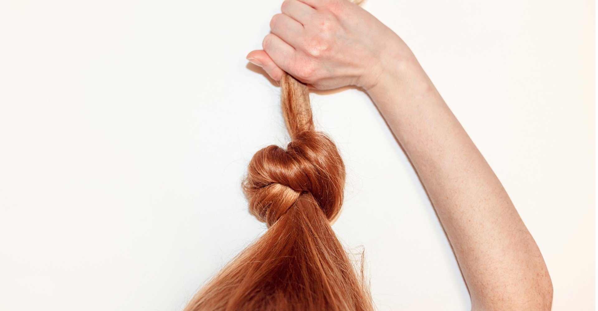 Modelo branca fazendo nó em seu cabelo ruivo e liso