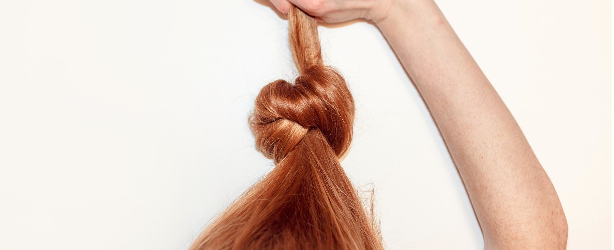 Modelo branca fazendo nó em seu cabelo ruivo e liso