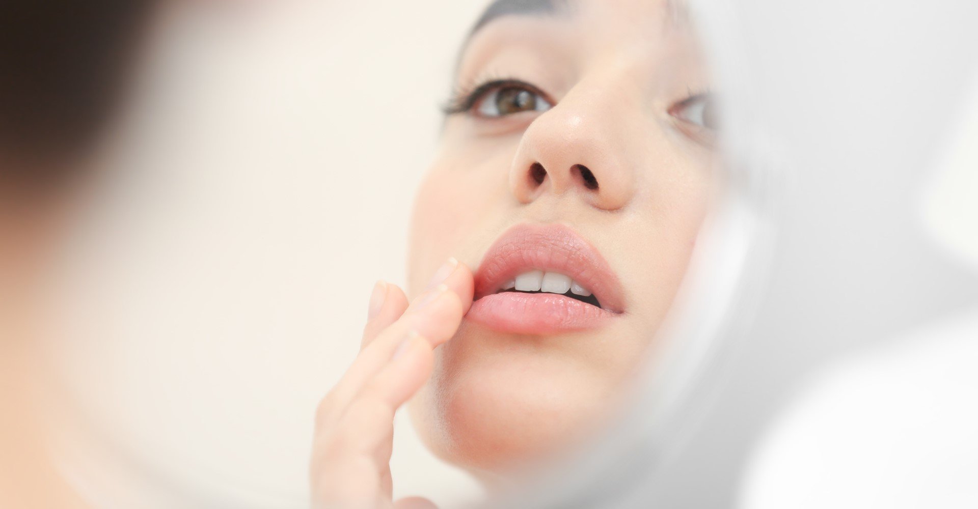 Modelo se olhando no espelho passando produto nos lábios