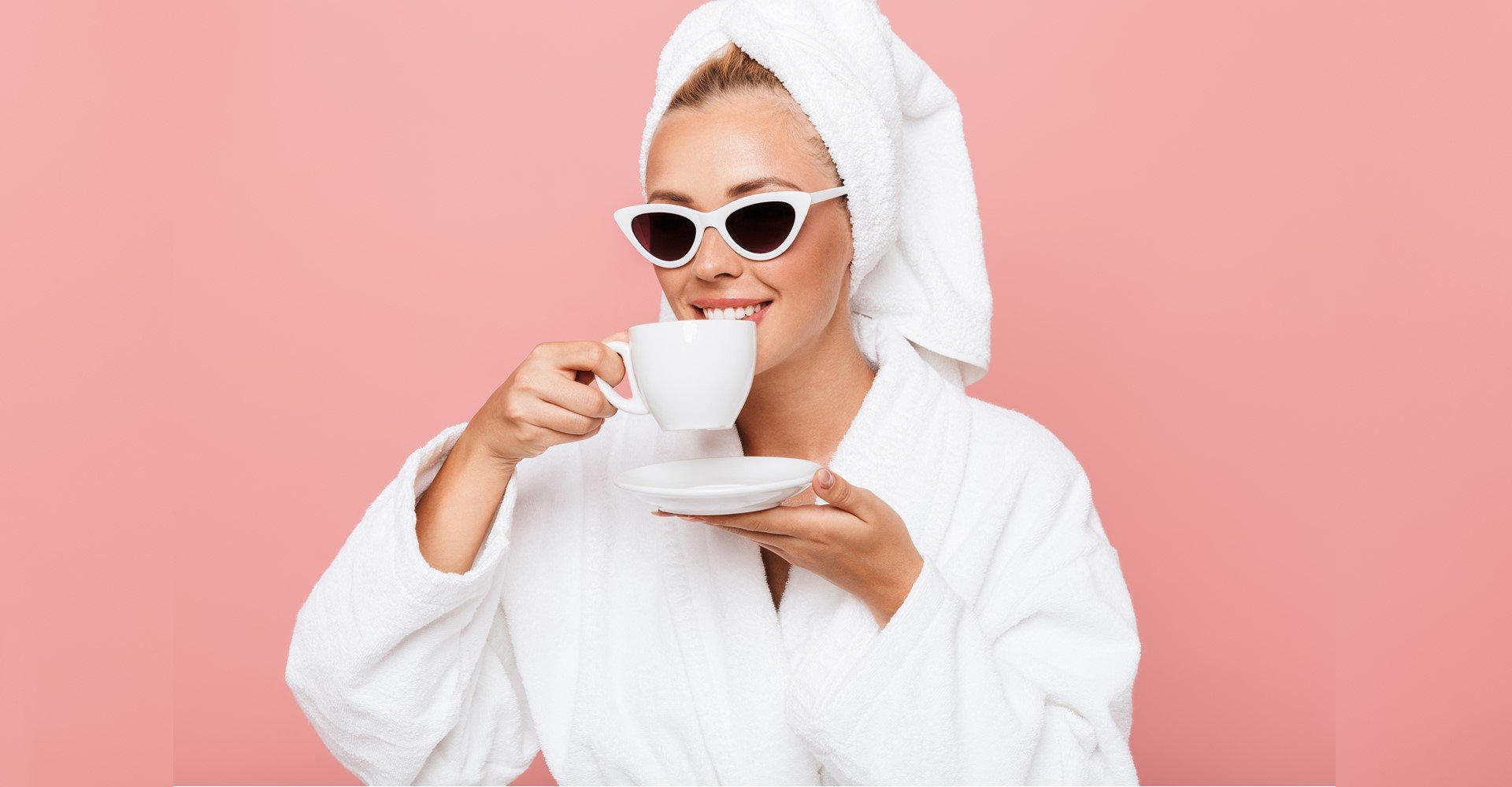 Modelo branca com toalha na cabeça e óculos de sol tomando café