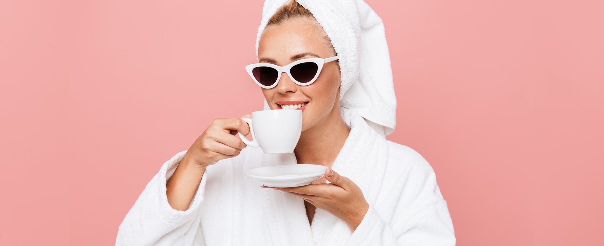 Modelo branca com toalha na cabeça e óculos de sol tomando café