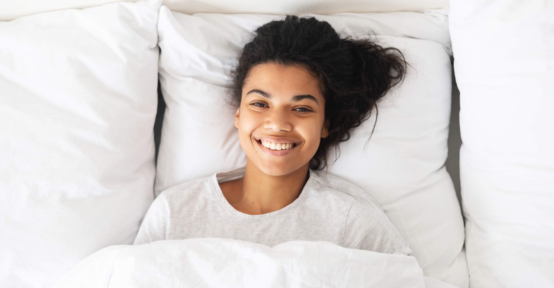 Modelo negra deitada na cama sorrindo