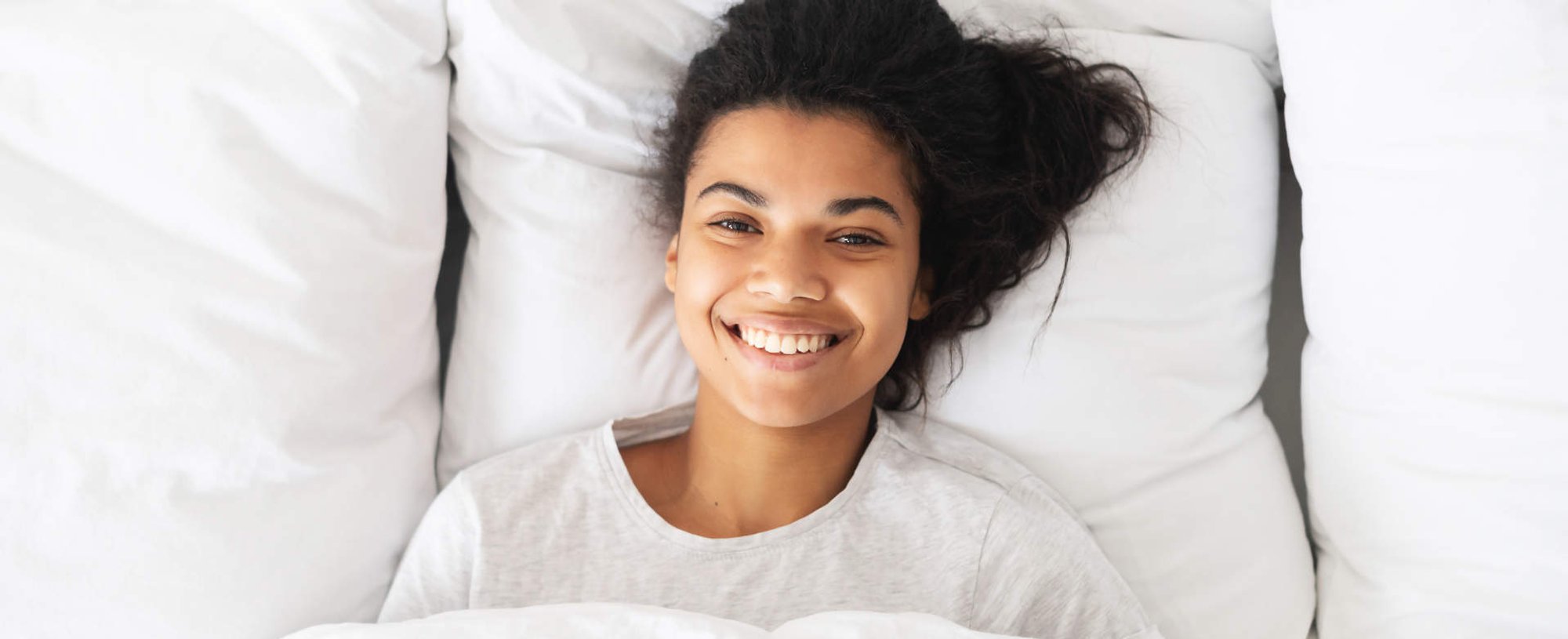 Modelo negra deitada na cama sorrindo