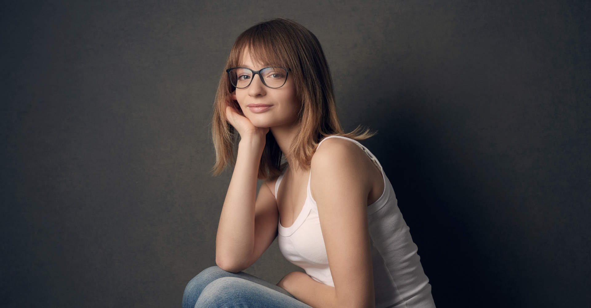 Modelo branca com óculos de grau e cabelo loiro com franja