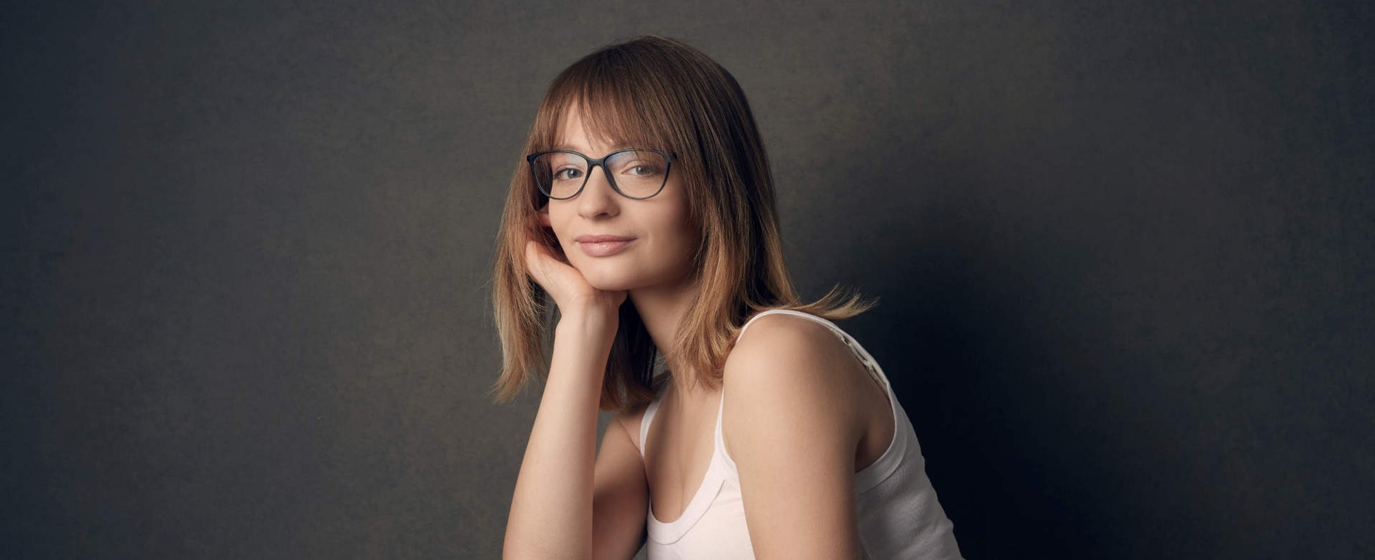 Modelo branca com óculos de grau e cabelo loiro com franja