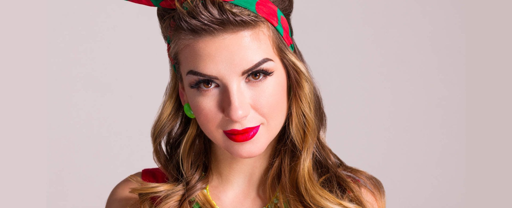 Modelo branca com batom vermelho e tiara colorida no cabelo
