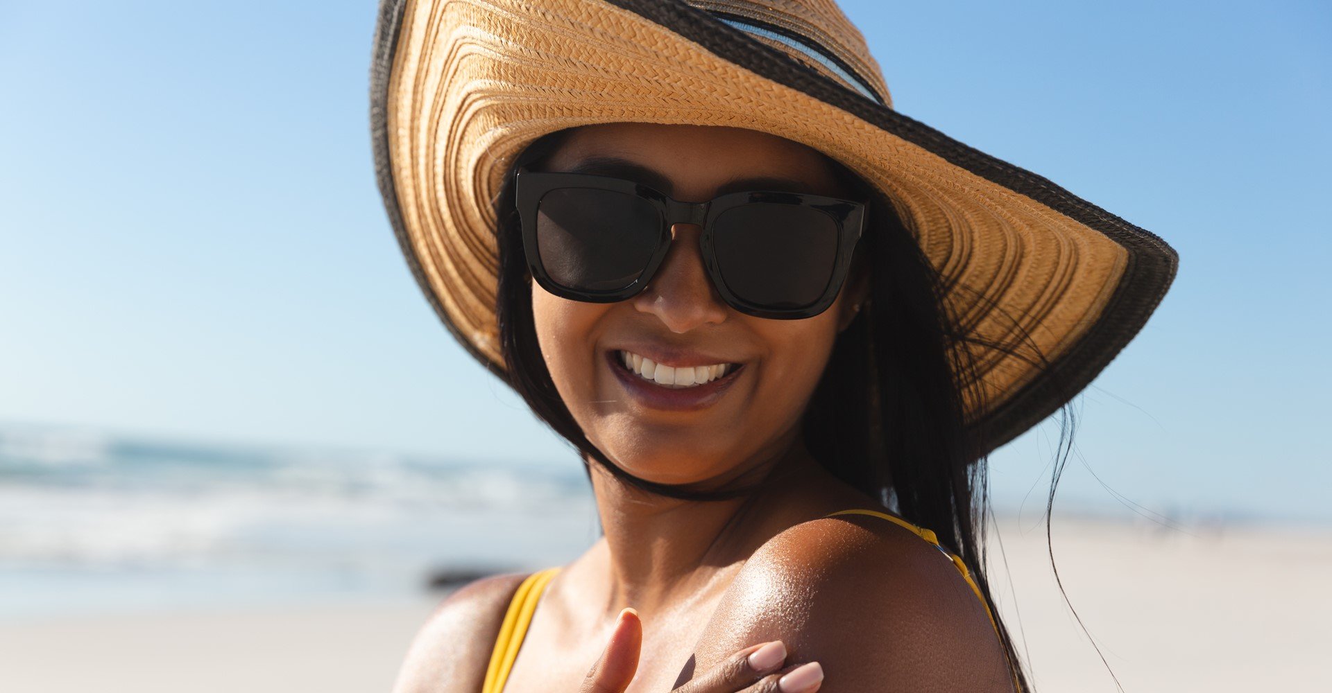 Modelo bronzeada com chapéu e óculos de sol