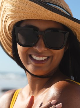 Modelo bronzeada com chapéu e óculos de sol