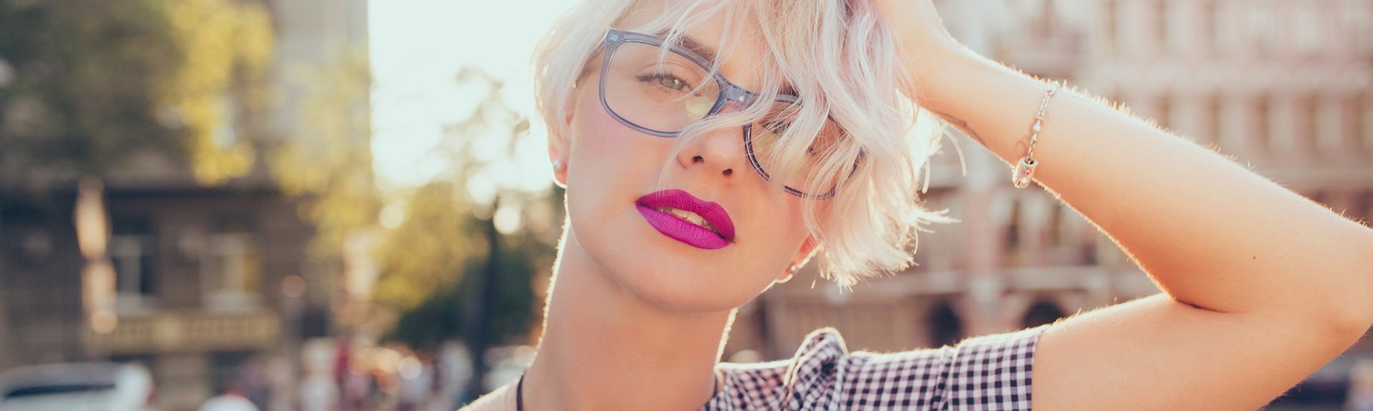 Modelo branca com cabelo platinado de óculos de grau posando para a foto