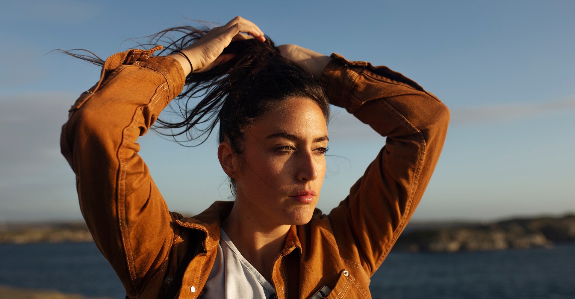 Modelo branca amarrando o cabelo