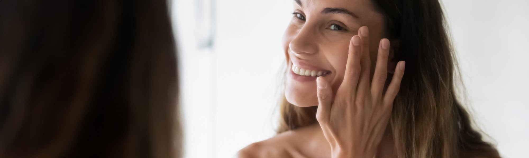 Modelo branca sorrindo se olhando no espelho