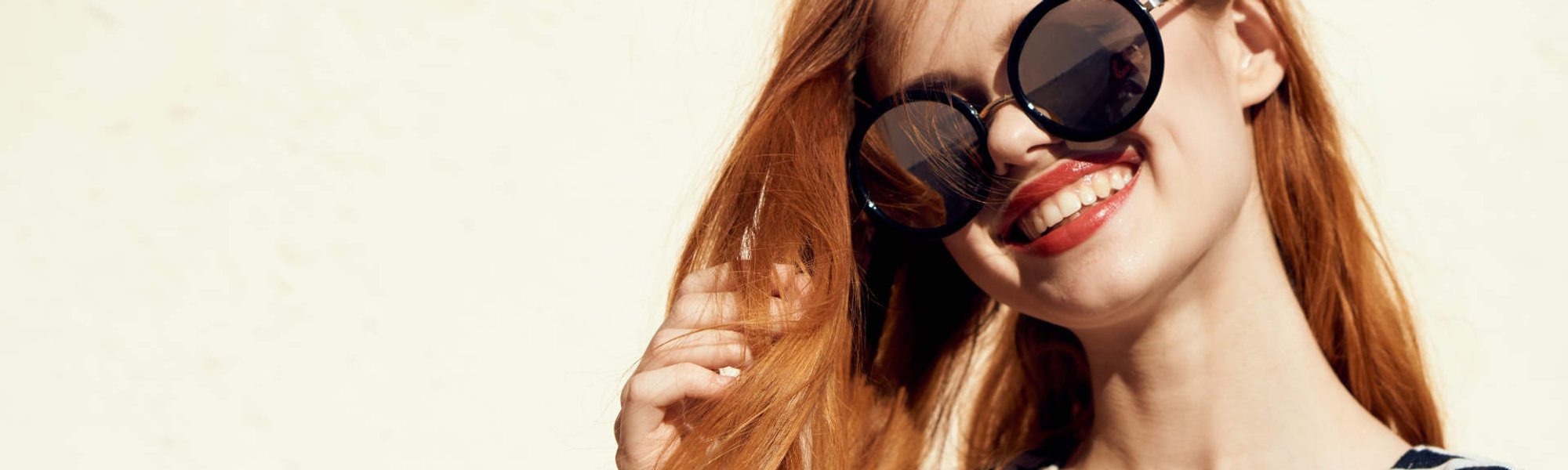 Modelo ruiva sorrindo com óculos de sol