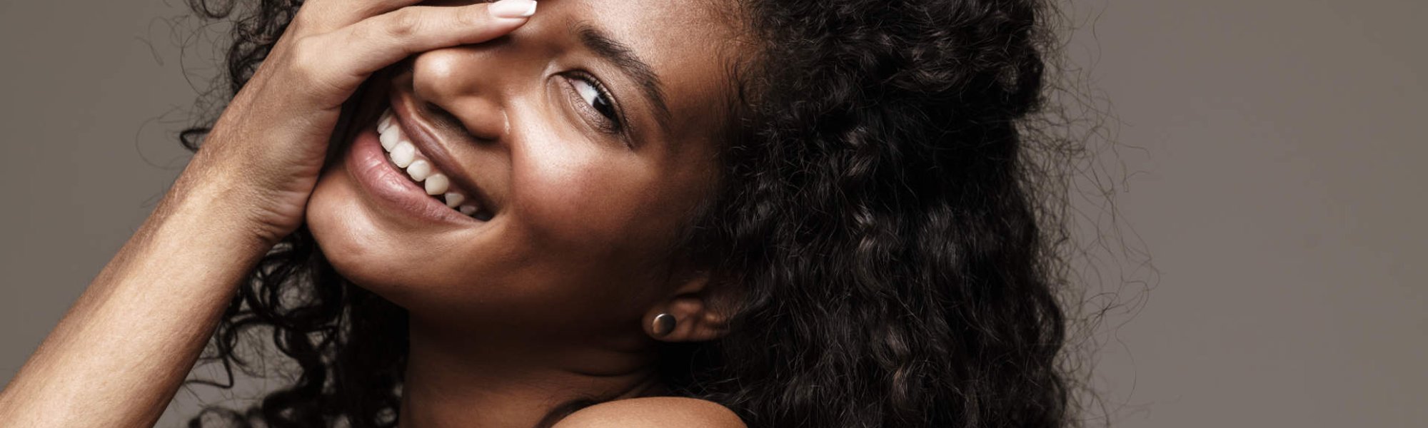 Modelo negra com cabelo cacheado e sorrindo