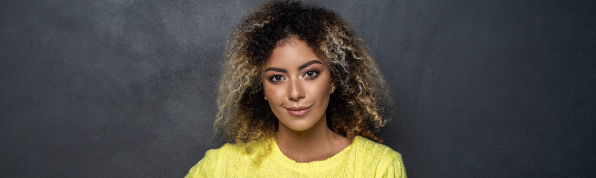 mulher exibe cabelos cacheados com coloração