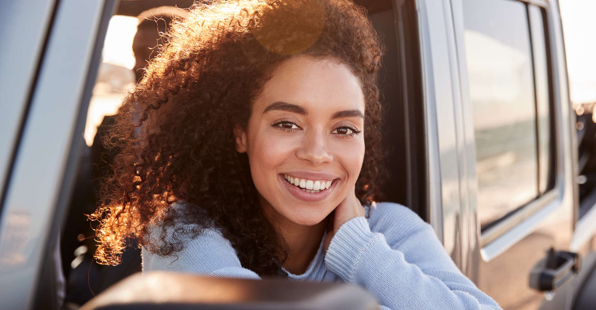 mulher desfruta do seu cabelo ao vento enquanto dirige